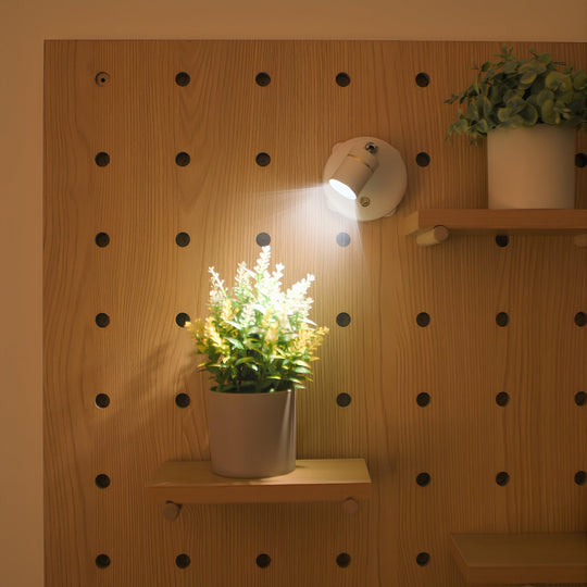 Zelfklevende spotlights verlichten een decoratieve plank met planten.
